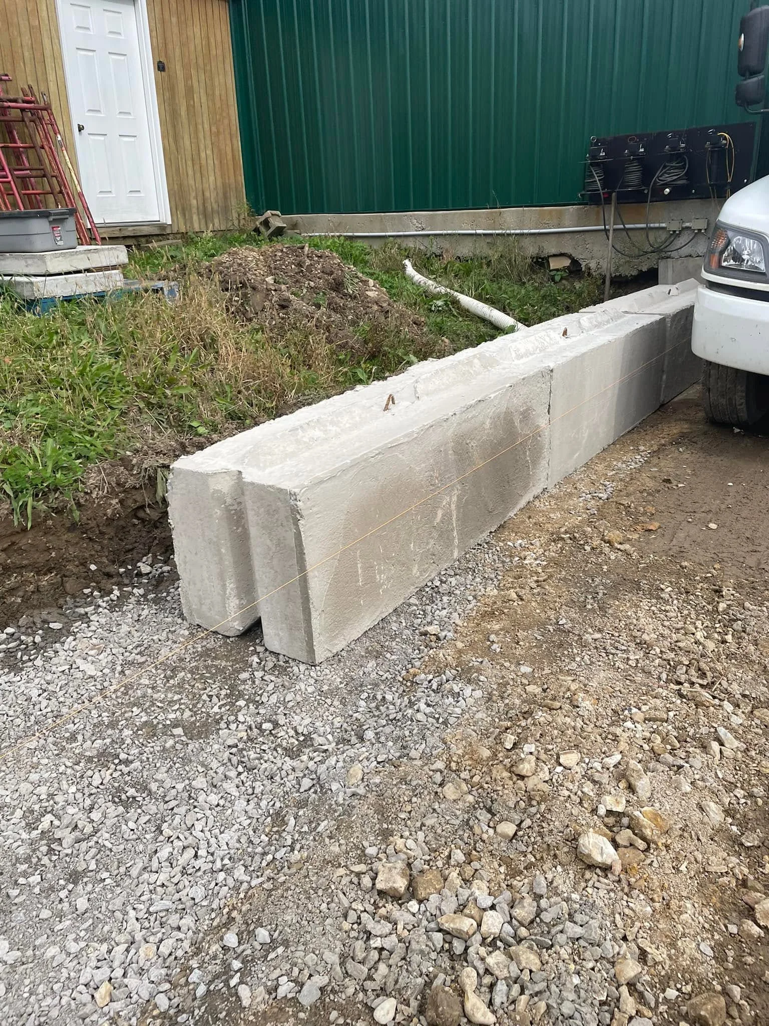 Precast concrete retaining wall blocks installed on gravel base with proper drainage setup