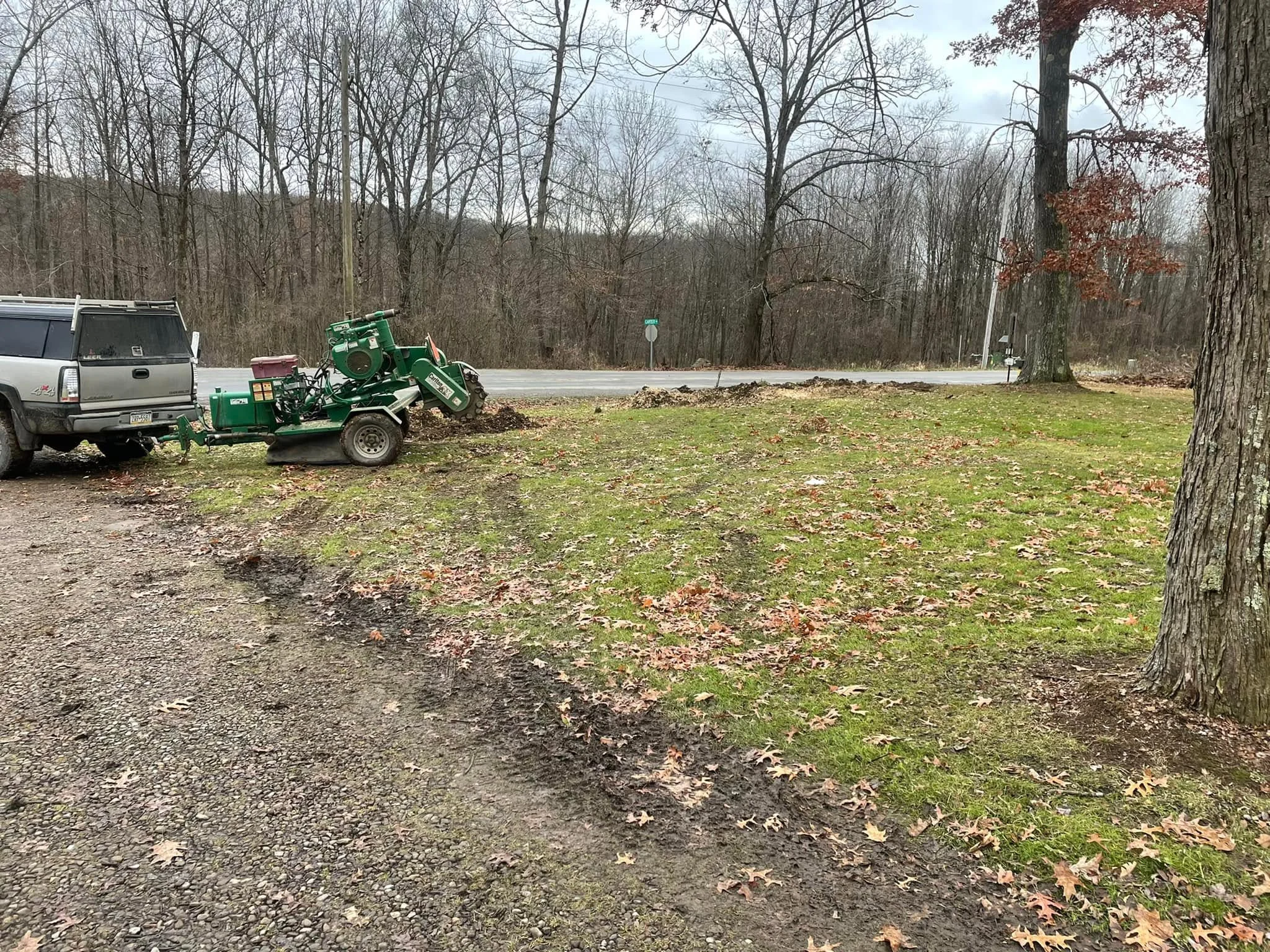 Green wood chipper and gravel driveway preparation on wooded residential lot