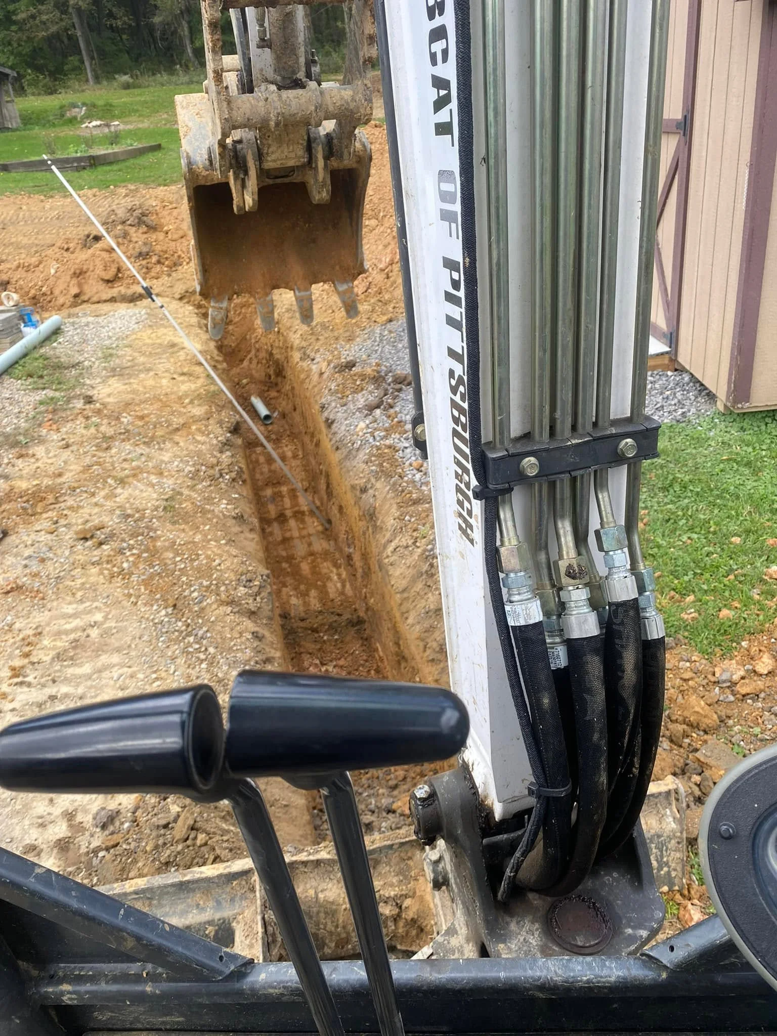 Caterpillar mini excavator digging utility trench with hydraulic bucket and gravel base